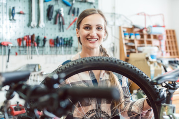 Bike mechanic woman looking through the wheel of bicycle