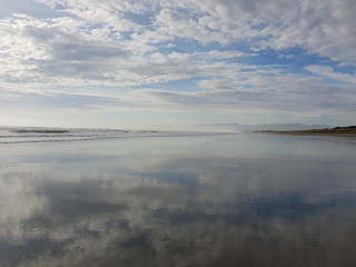 Obraz premium Reflections of a cloudy sky on a calm beach landscape. Waimairi Beach, Christchurch.