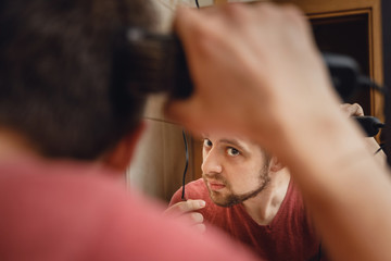 A man cuts his hair on his head with an electric razor 