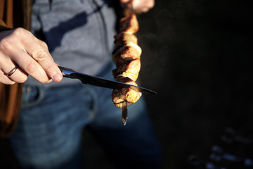 skewers kebab in hand. A man cooks meat on coals on the street