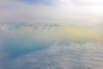 Sun rise in the morning of blue sky above the white clouds and land background with golden light looking through an airplane window
