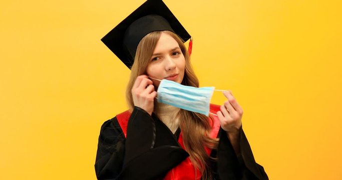 Happy graduate in a master's dress, on a yellow background. Concept of the graduation ceremony