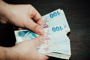 Many hundred Turkish lira on wooden table background texture. bundles of money scattered on the...