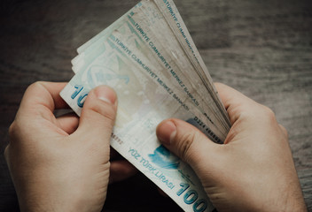 Many hundred Turkish lira on wooden table background texture. bundles of money scattered on the office desk. wealth and income concept. Counting money. 