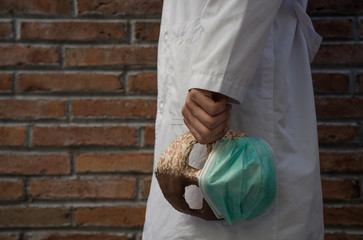 Doctor con bata blanca y una mascara en la mano con cubre boca