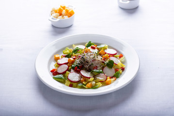mixed salad on a white tablecloth surrounded by some ingredients