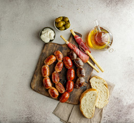 roasted spanish sausages on the cutting board - butifarra blanca, chorizo, morcilla de cebolla,...