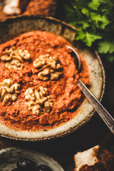 Turkish traditional spicy smoked red pepper paste with walnuts, simit bagels, fresh parsley and olives over breakfast table, selective focus. Typical Turkish breakfast dish