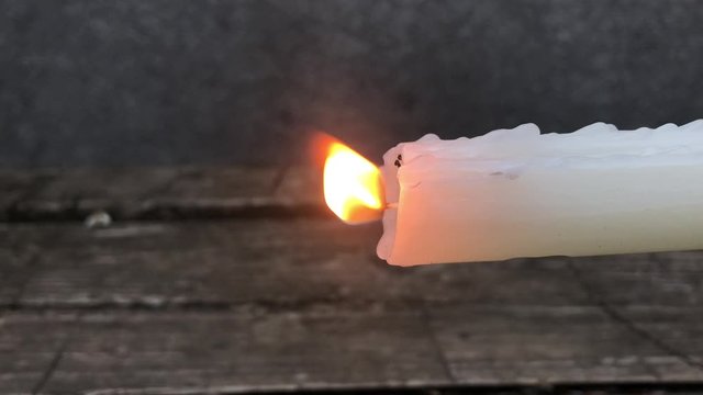 tilted burning candle in the wind with dripping paraffin