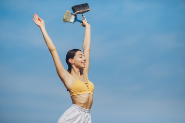 Beautiful girl standing on a sky background. Woman in a yellow top. Lady with tools in her hands
