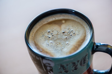 Close up of a espresso coffee with a heart on wooden background