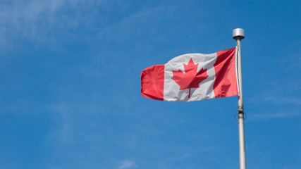 Canadian flag pole on blue sky with copy space background. Canada flag country maple leaf symbol and nationalism concept