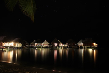 Fototapeta na wymiar luxury beach resort with overwater bungalows by night