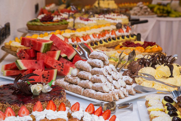 buffet with sweets. fruits and other sweets on dessert table. Rows of tasty looking desserts in beautiful arrangements. Sweets on banquet table - picture taken during catering event