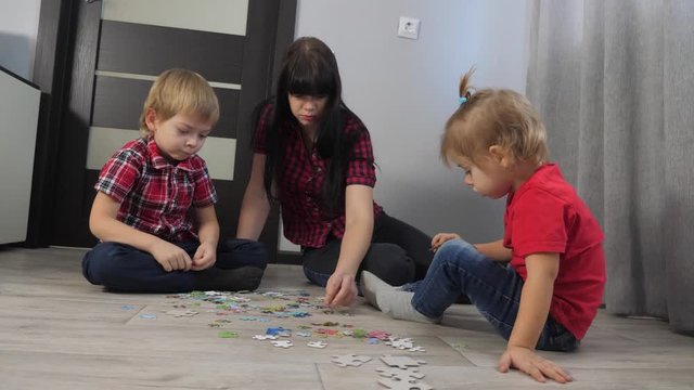 happy family collection puzzles teamwork. development of fine motor skills and thinking. lifestyle little boy and girl with mom a collect mosaic puzzles