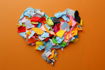 Torn colored paper metaphorically depicts a heart on an orange background