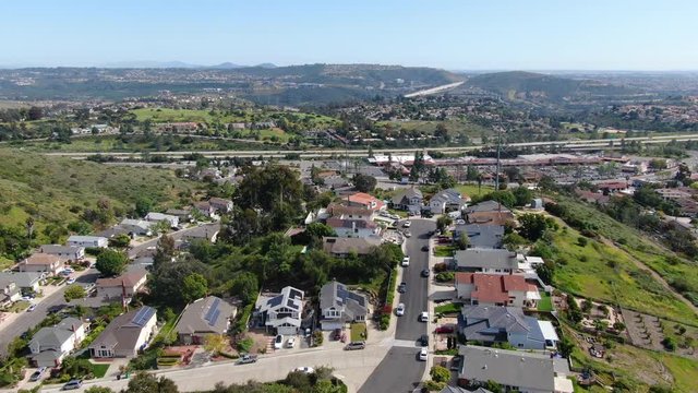 Aerial view of upper middle class neighborhood with residential house and swimming pool in a valley with mountain on the background in San Diego, California, USA.