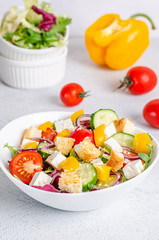 White plate with mix vegetable salad, greens, crackers and sesame seeds on a light background.