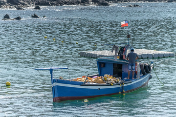 Fishing boat anchored in the beach after a working day fishing in the Pacific Ocean. A blue boat...