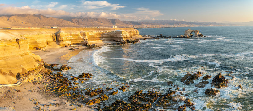 "La Portada de Antofagasta" (Antofagasta Cover) is a natural monument created by the sea and wind erosion creating a small island with a natural stone arch in front of the orange cliffs at sunset time