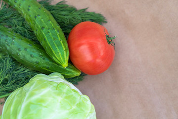 Eco-vegetables on a paper background close-up with a copy space. Tomatoes, cucumbers, dill top view. Soft focus.