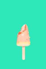 half eaten white chocolate outer popsicle with red inner on green background