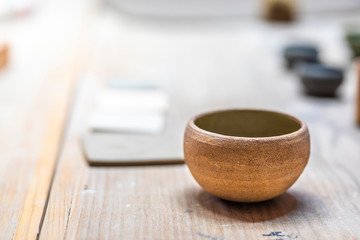 A clay pot over a wooden table at a traditional workshop showing their handmade products. A detailed textured view of the old fashion craft design pot with a low depth of field inside the artisan shop