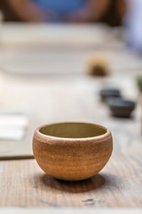 A clay pot over a wooden table at a traditional workshop showing their handmade products. A detailed textured view of the old fashion craft design pot with a low depth of field inside the artisan shop