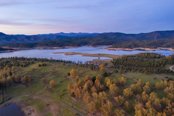 Aerial view of Gabriel y Galan lake at Extremadura countryside. An amazing view during sunset time on a cloudy day. The colors of the sky reflected over the lake waters give an idyllic landscape view
