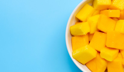 Tropical fruit, Mango cube slices in white bowl on blue background.