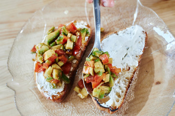 close up spread the tomato and avocado on the bread with cheese 