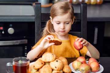 Healthy and harmful food during quarantine, self-isolation. The little blonde girl chooses to take...