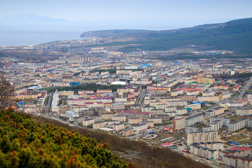 View from the mountains on the city of Magadan. Cityscape with streets and buildings. Sea bay in the distance. The city of Magadan is the administrative center of the Magadan Region of Russia. Siberia