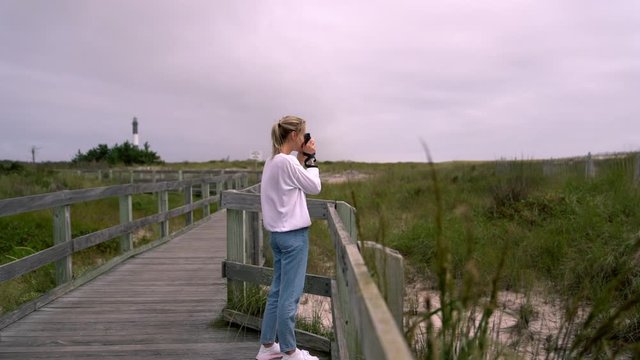 Millennial hipster girl wanderlust photographing nature landscape during holidays, happy female tourist taking photos on camera while enjoying summer vacations exploring National Park, slow motion
