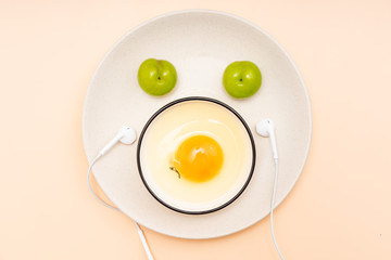 Eggs, green plums, headphones are placed in the shape of a smiling face