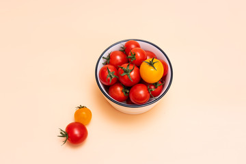 Bowl filled with cherry tomatoes and small tomatoes on orange background