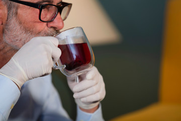 man with medical gloves drinking a cup of tea