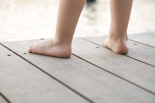 Barefoot toddlers feet standing on the wooden floor