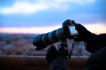 A hand holding a SLR camera taking pictures at dawn
