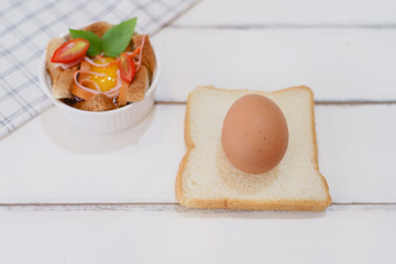 Homemade tomato egg cup delicious breakfast on white wooden table with egg bread and rolling pin with copy space. Cooking at home concept.