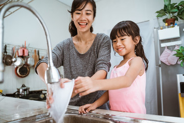 happy kid enjoy washing the dishes together with mother in the kitchen