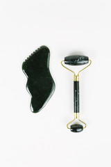 Black obsidian jade roller and gua sha stone for lymphatic facial massage / overhead flat lay on...