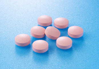 Pink pills placed on blue background
