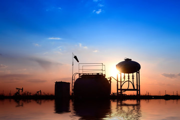 Fototapeta na wymiar Oil tanks, silhouetted against the setting sun