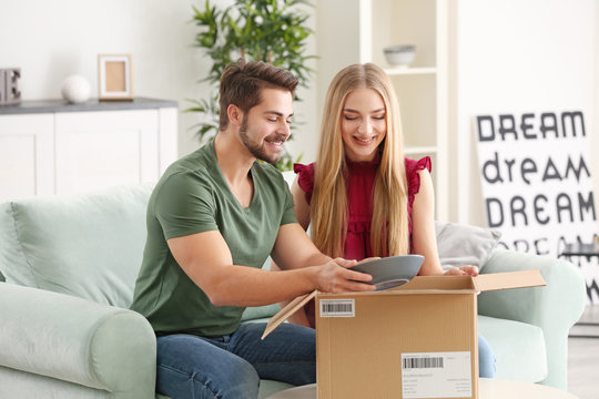 Young couple unpacking parcel at home