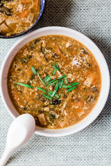 A Delicious Chinese Hot and Sour Soup Served in a White Bowl with a Spoon Resting on Bowl