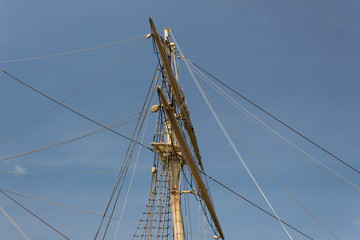 Block and tackle, shrouds, and mast on an old sailboat, blue sky, horizontal aspect
