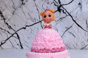 Princess doll cake with dress made of cream on marble pattern background.