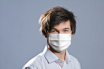 portrait of handsome young man on grey background. man wearing protective mask against infectious diseases and flu. Health care concept.