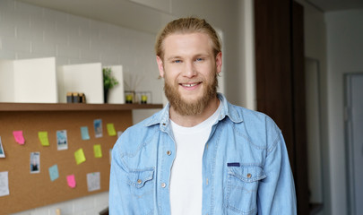Positive young hipster professional man student, freelancer standing at home office. Young confident smiling adult caucasian bearded casual guy looking at camera. Head shot close up portrait. - obrazy, fototapety, plakaty